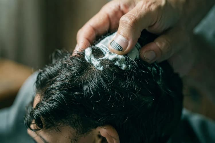 Mãos aplicando balm na barba com movimentos de massagem