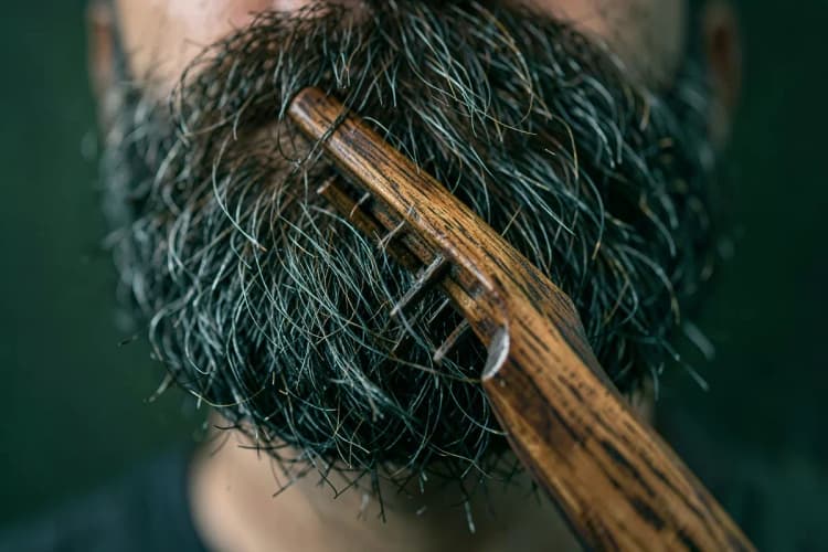 Pente de madeira passando por uma barba cheia e bem cuidada.